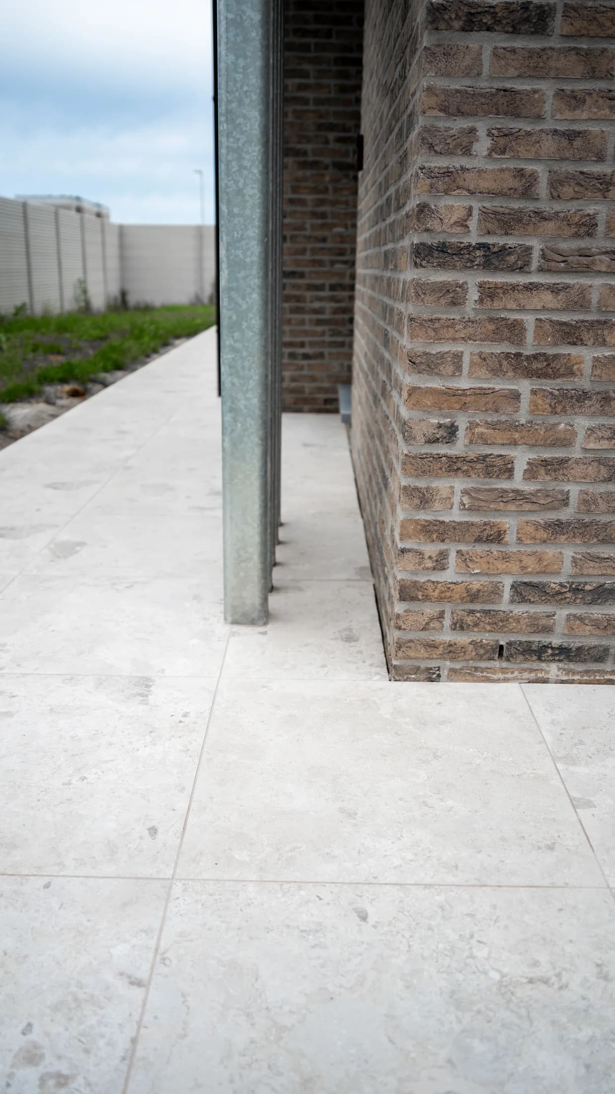 Licht natuursteenlook terras bij een bakstenen woning